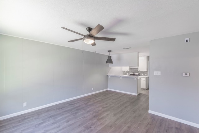 unfurnished living room featuring ceiling fan, a textured ceiling, and dark hardwood / wood-style floors