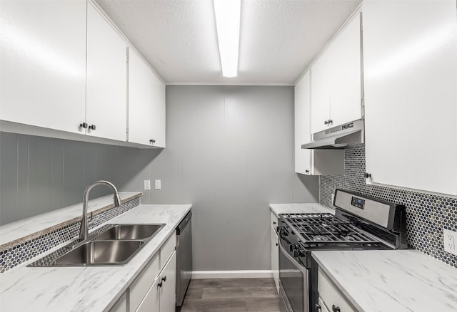 kitchen with appliances with stainless steel finishes, decorative backsplash, white cabinets, hardwood / wood-style flooring, and sink