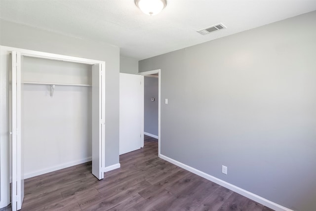 unfurnished bedroom with a closet, dark hardwood / wood-style floors, and a textured ceiling