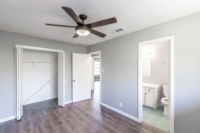 unfurnished bedroom with a closet, wood-type flooring, ceiling fan, and ensuite bathroom