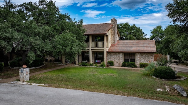 view of front of house with a balcony and a front lawn