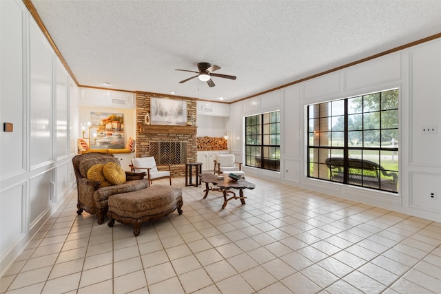 living room featuring a fireplace, crown molding, light tile patterned floors, a textured ceiling, and ceiling fan