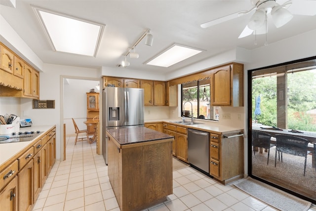 kitchen with a kitchen island, stainless steel appliances, sink, light tile patterned floors, and ceiling fan