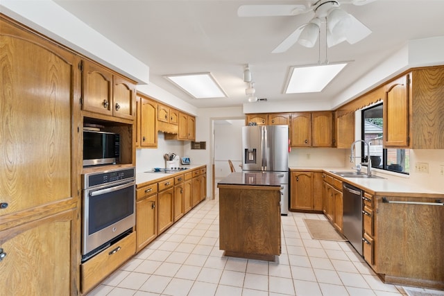 kitchen featuring ceiling fan, appliances with stainless steel finishes, sink, a skylight, and a center island