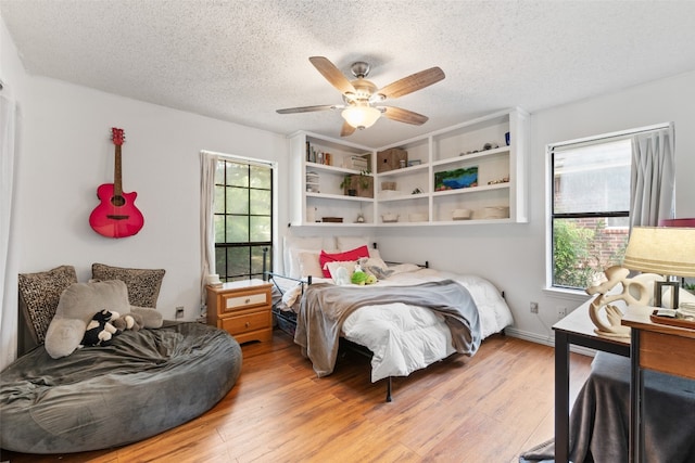 bedroom featuring a textured ceiling, light wood-type flooring, and ceiling fan