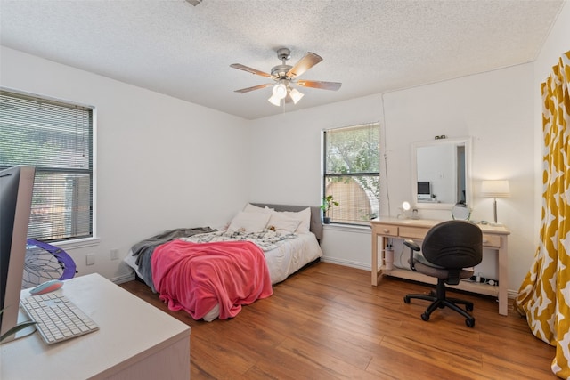 bedroom with a textured ceiling, hardwood / wood-style flooring, and ceiling fan