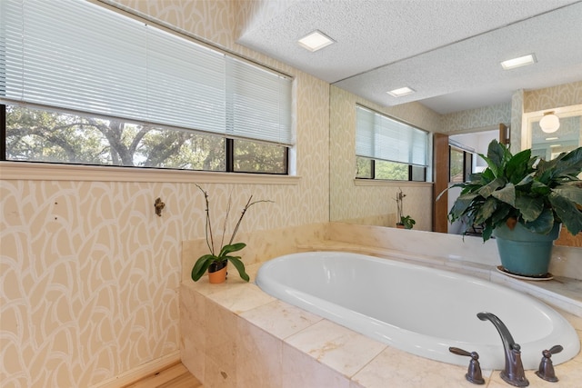 bathroom with a textured ceiling and tiled bath