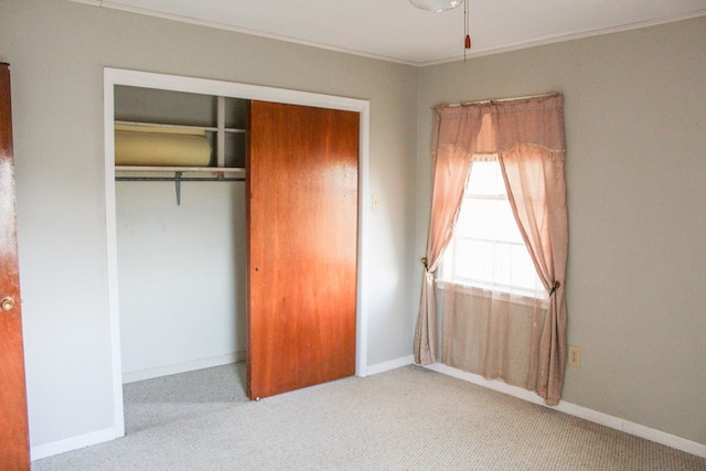 unfurnished bedroom featuring ornamental molding, light carpet, and a closet