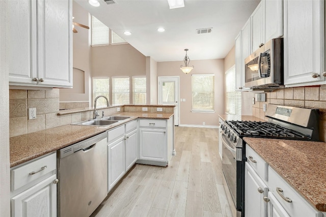 kitchen featuring appliances with stainless steel finishes, white cabinets, pendant lighting, light hardwood / wood-style flooring, and sink