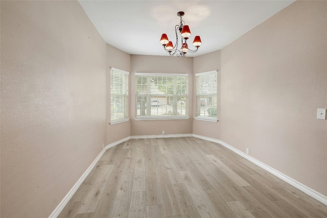 spare room featuring an inviting chandelier and light hardwood / wood-style floors