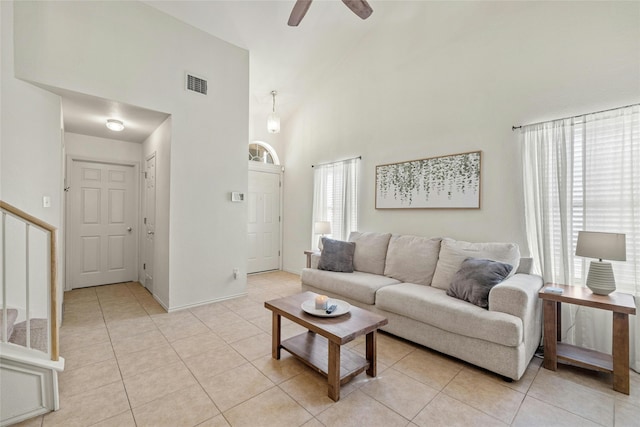 tiled living room with ceiling fan and a high ceiling