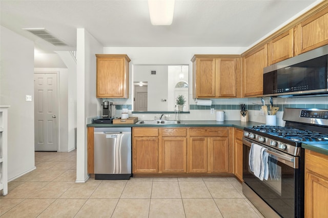 kitchen with appliances with stainless steel finishes, backsplash, light tile patterned floors, and sink