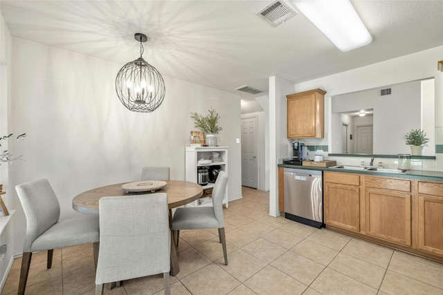 kitchen featuring pendant lighting, sink, stainless steel dishwasher, light tile patterned floors, and a chandelier