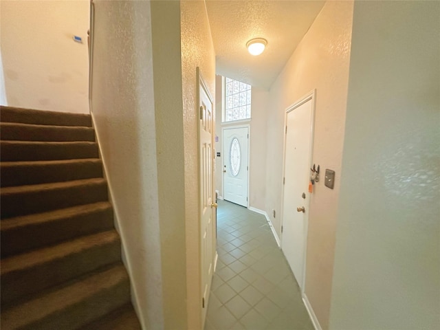 hallway featuring dark tile patterned flooring, vaulted ceiling, and a textured ceiling