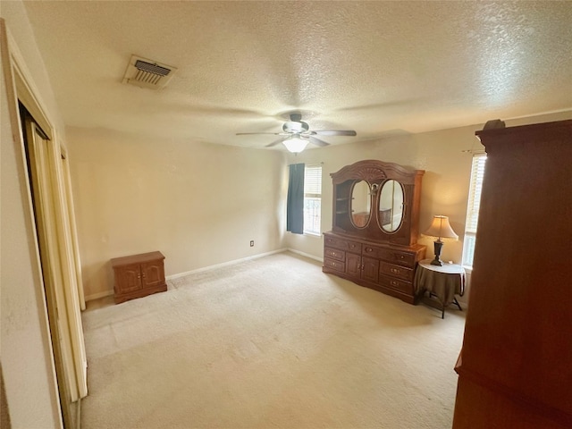 unfurnished bedroom featuring a textured ceiling, light carpet, ceiling fan, and a closet