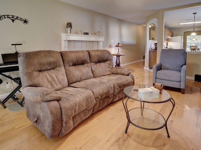 living room with a tiled fireplace and light hardwood / wood-style floors