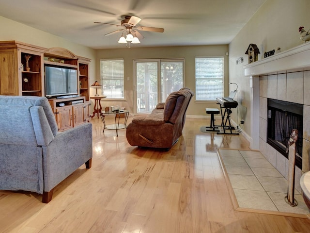 living room with ceiling fan, a fireplace, and light hardwood / wood-style floors