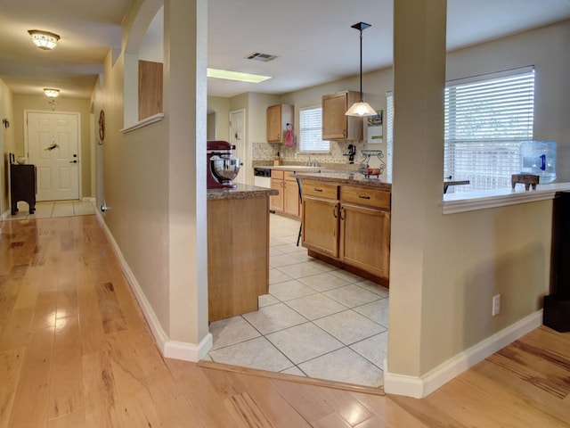 kitchen with light hardwood / wood-style flooring, a wealth of natural light, backsplash, and hanging light fixtures