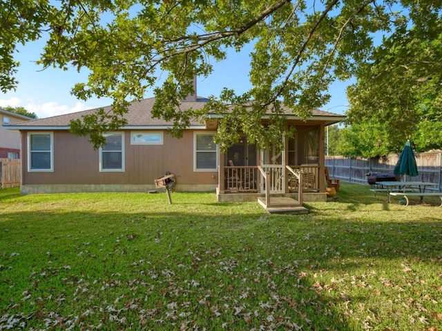 rear view of house featuring a sunroom and a lawn