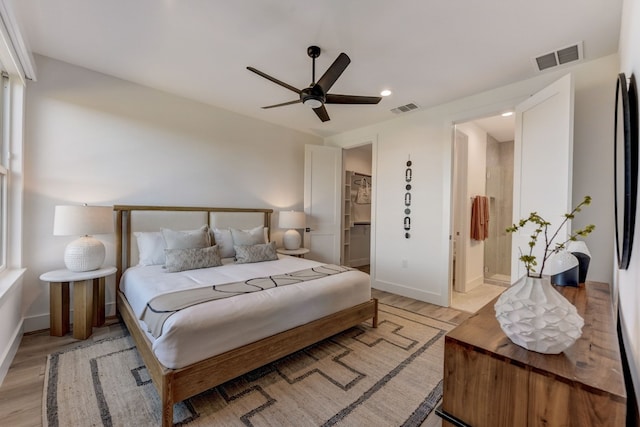 bedroom featuring ensuite bath, ceiling fan, and light wood-type flooring