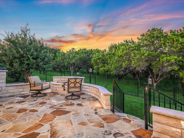 patio terrace at dusk with a lawn and an outdoor fire pit