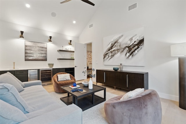 living room with ceiling fan, high vaulted ceiling, light hardwood / wood-style floors, and beverage cooler