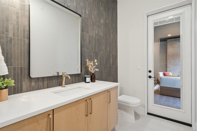 bathroom with toilet, vanity, tile patterned floors, and tile walls