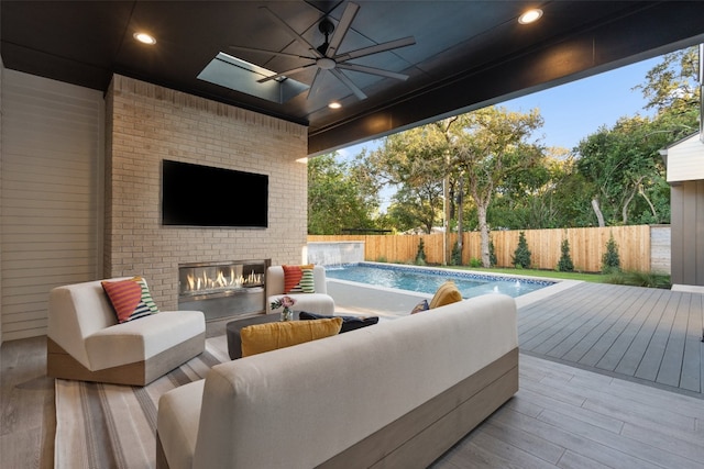 view of patio featuring an outdoor brick fireplace, ceiling fan, and a pool side deck