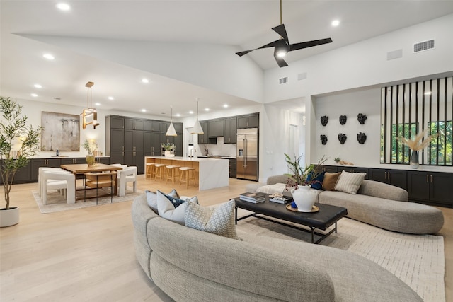 living room featuring ceiling fan, light wood-type flooring, and high vaulted ceiling