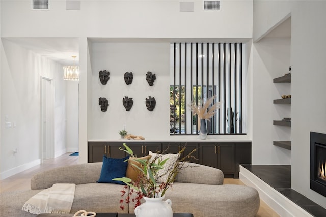 living room featuring a notable chandelier, light wood-type flooring, and built in features