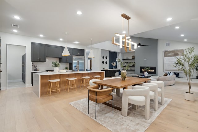 dining room with light wood-type flooring and vaulted ceiling