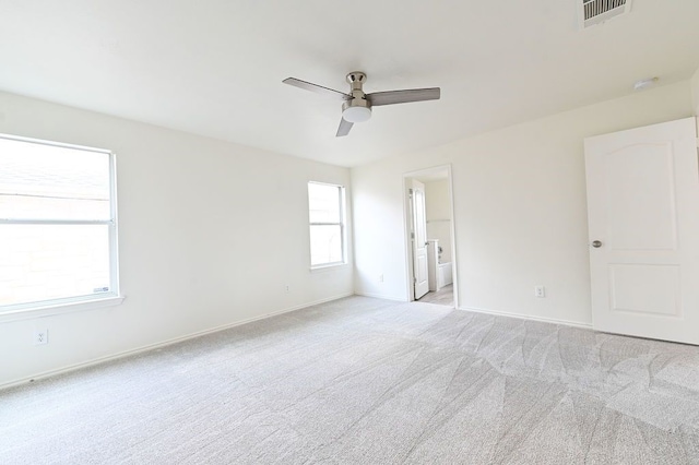 unfurnished bedroom with ceiling fan, light colored carpet, and ensuite bathroom