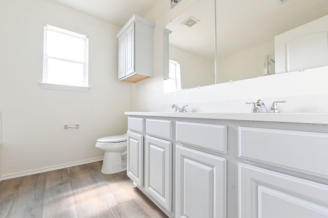 bathroom featuring a healthy amount of sunlight, vanity, toilet, and hardwood / wood-style flooring