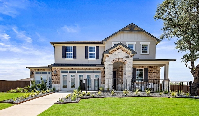 view of front of house with covered porch, a front yard, and french doors