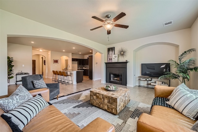 living room with ceiling fan, sink, and light tile patterned floors