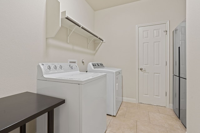 clothes washing area featuring light tile patterned floors and washer and clothes dryer