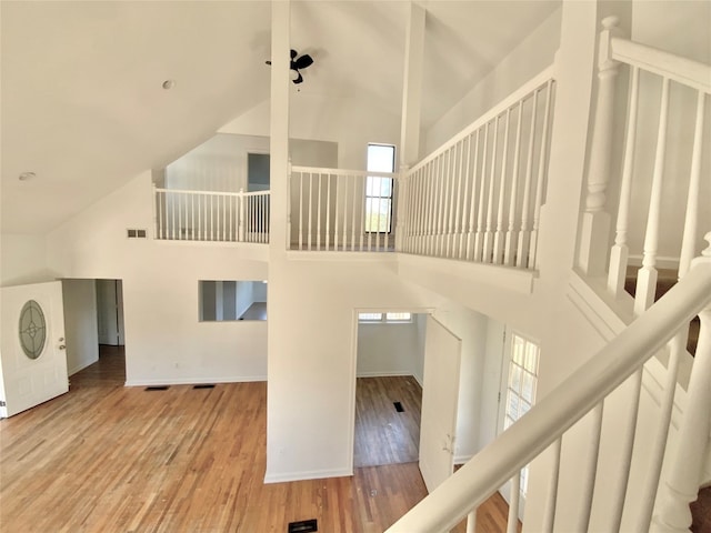 stairway featuring hardwood / wood-style flooring and high vaulted ceiling