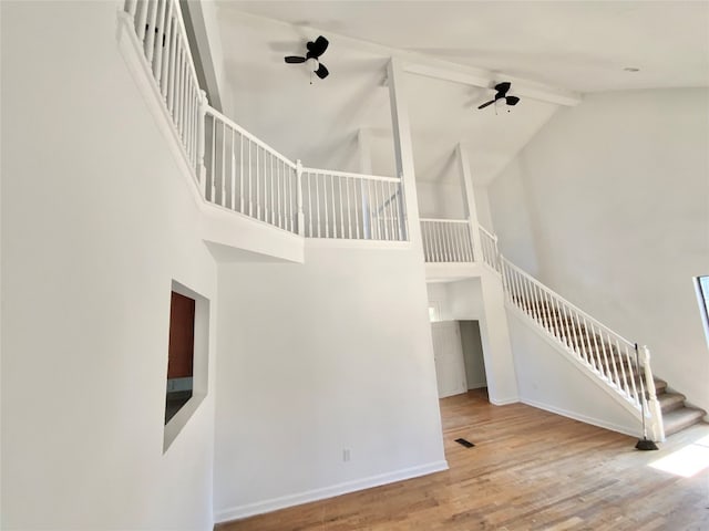 stairway with beam ceiling, hardwood / wood-style flooring, and high vaulted ceiling