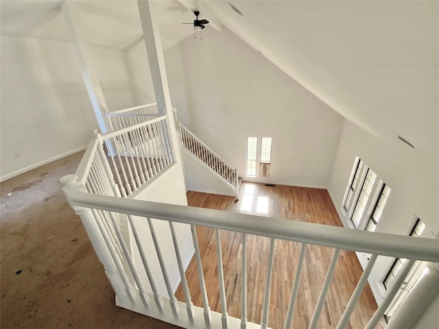 staircase with hardwood / wood-style floors, high vaulted ceiling, and ceiling fan