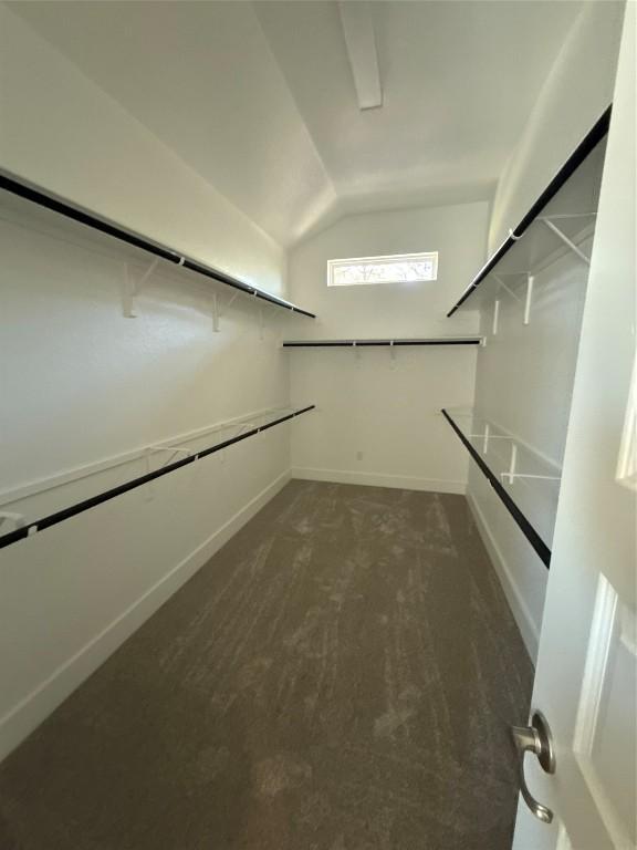 spacious closet with dark carpet and vaulted ceiling