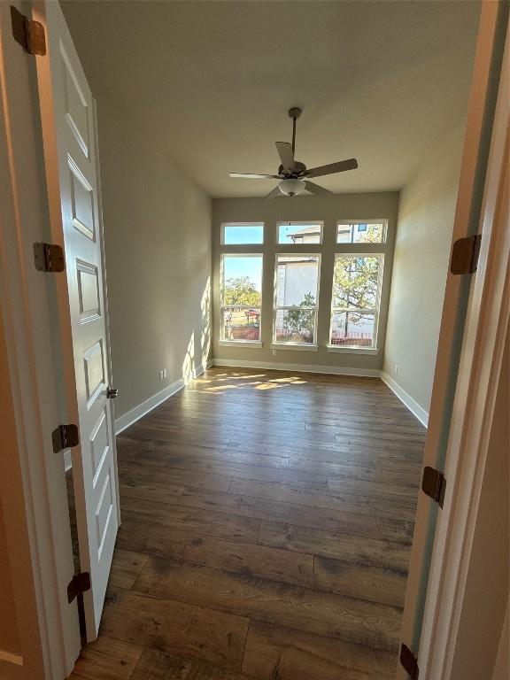 empty room featuring dark hardwood / wood-style flooring, ceiling fan, and plenty of natural light