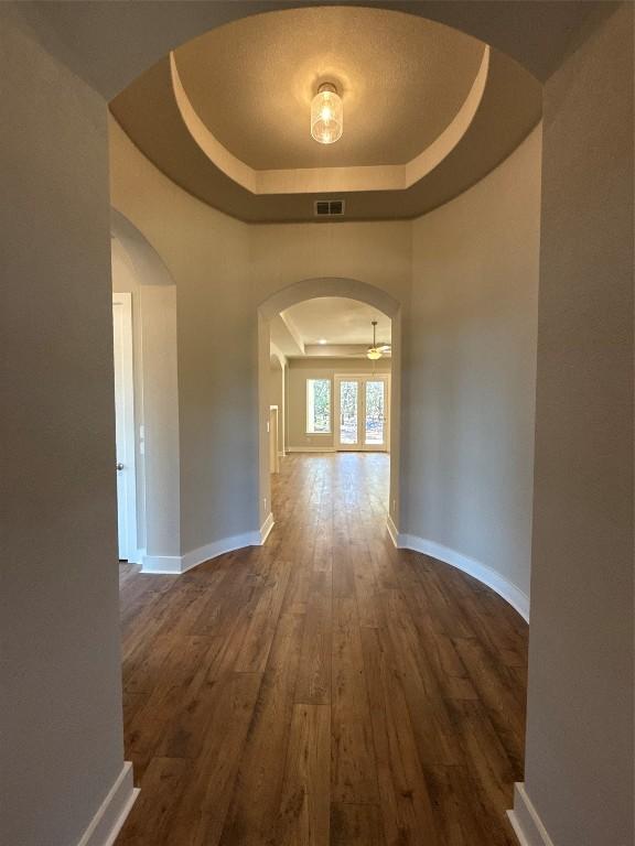 hallway with a tray ceiling and dark wood-type flooring