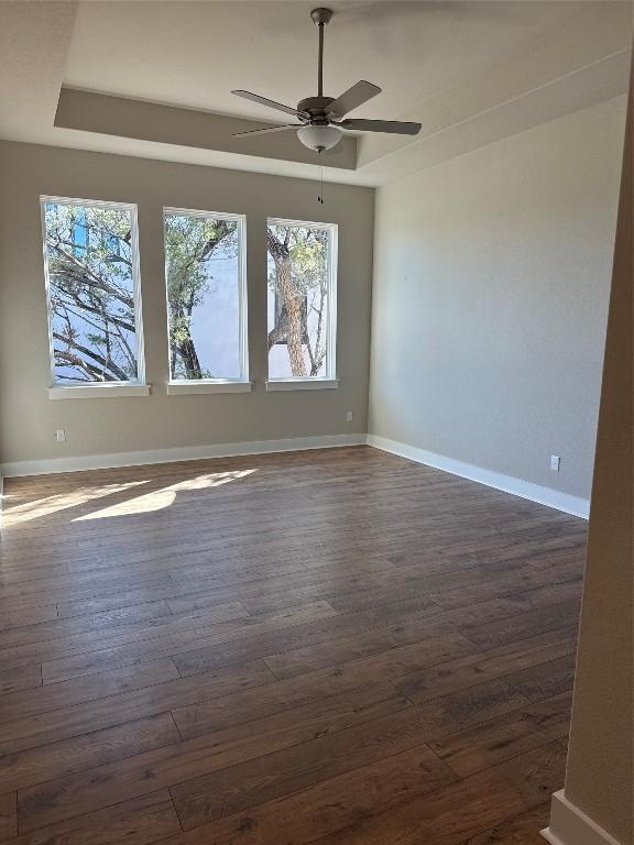 unfurnished room featuring dark hardwood / wood-style floors, plenty of natural light, and ceiling fan