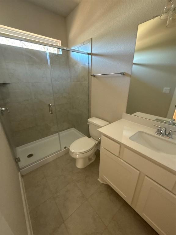 bathroom featuring tile patterned floors, a shower with door, vanity, and toilet