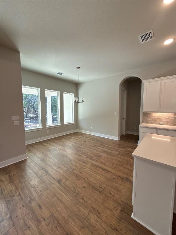 unfurnished living room featuring a notable chandelier and dark hardwood / wood-style floors