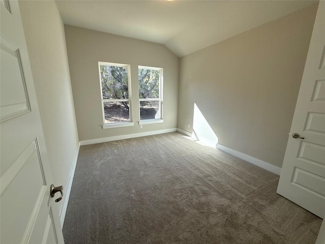 empty room with dark carpet and vaulted ceiling