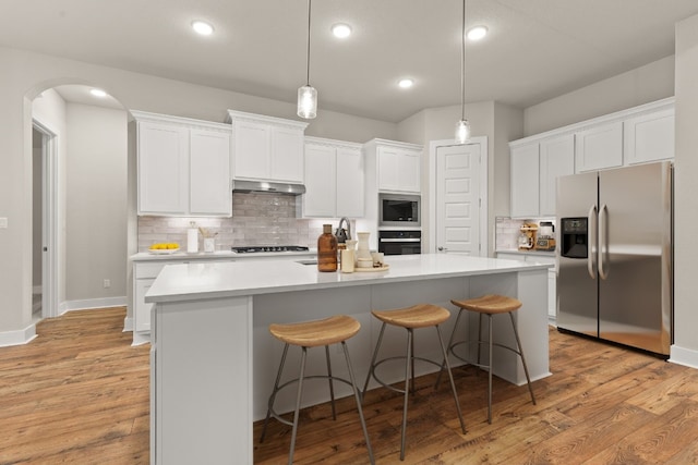 kitchen featuring built in microwave, an island with sink, oven, white cabinets, and stainless steel refrigerator with ice dispenser