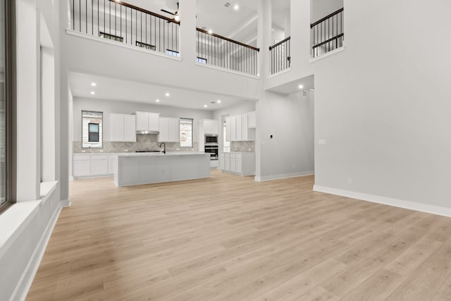 unfurnished living room featuring sink and light hardwood / wood-style flooring