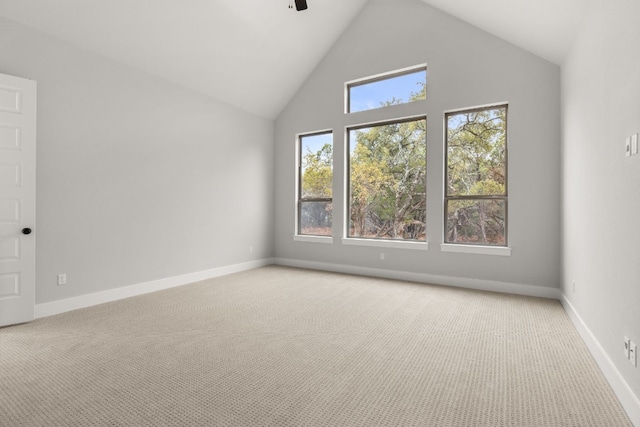 carpeted spare room with ceiling fan and high vaulted ceiling