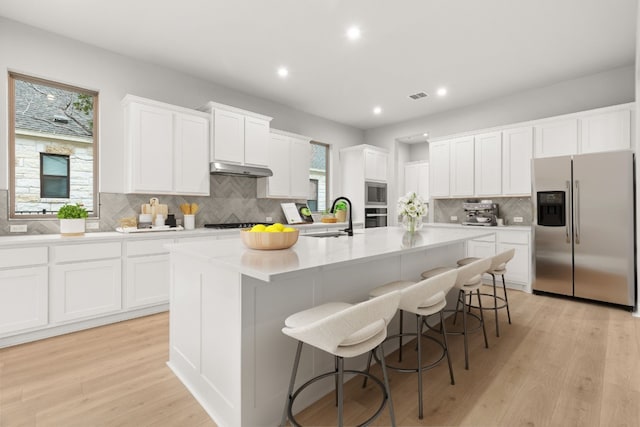 kitchen featuring stainless steel appliances, a center island with sink, and white cabinets